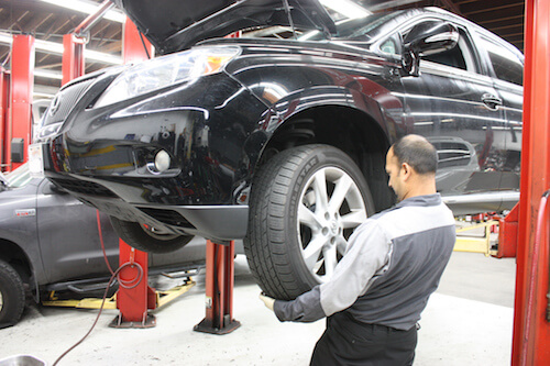Bring in your Lexus vehicle for maintenance A worker examining the tire of a Lexus vehicle at A+ Japanese Auto Repair in San Carlos, CA